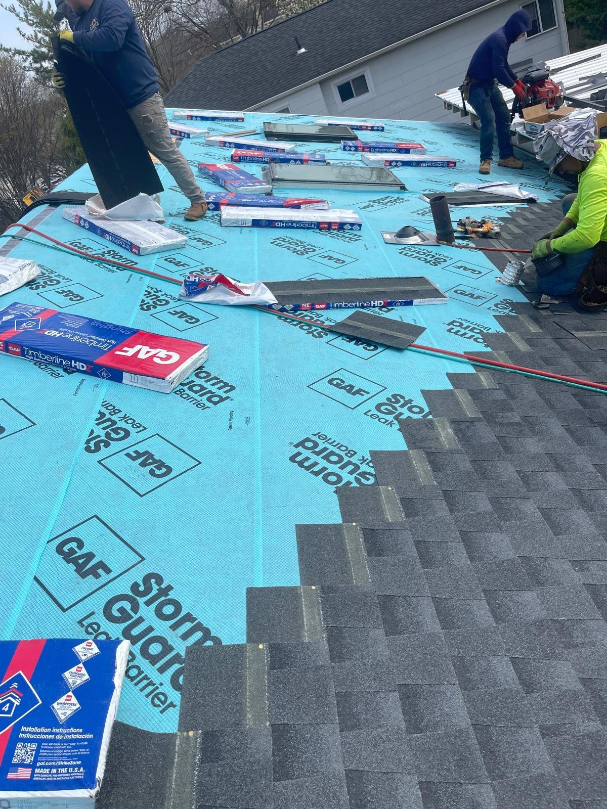 EZ Roofing and Builders crew installing GAF Timberline shingles over StormGuard leak barrier on a Long Island roof